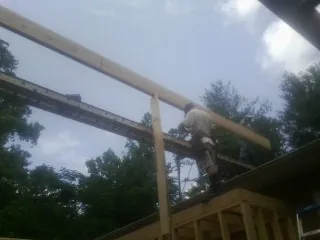 Carpenter setting a ridge beam over a new addition frame — Ice Dam Removal by Roofing Brothers in Amesville
