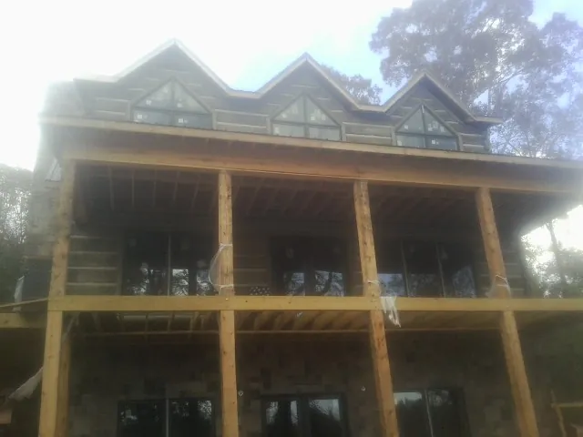 Dormers and porch framing on a large log home under construction — Roof Coating work by our crew in Amesville