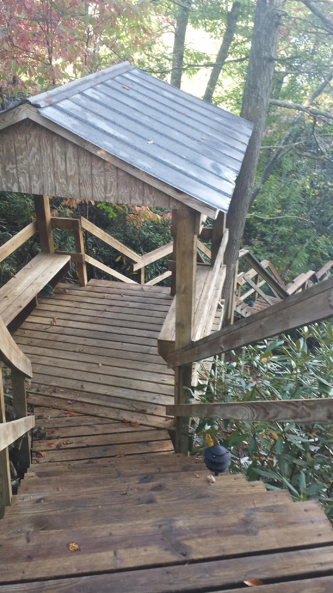 Metal roofed shelter over wooden steps on a wooded walkway — Skylight Repair & Installation work by our crew in Amesville