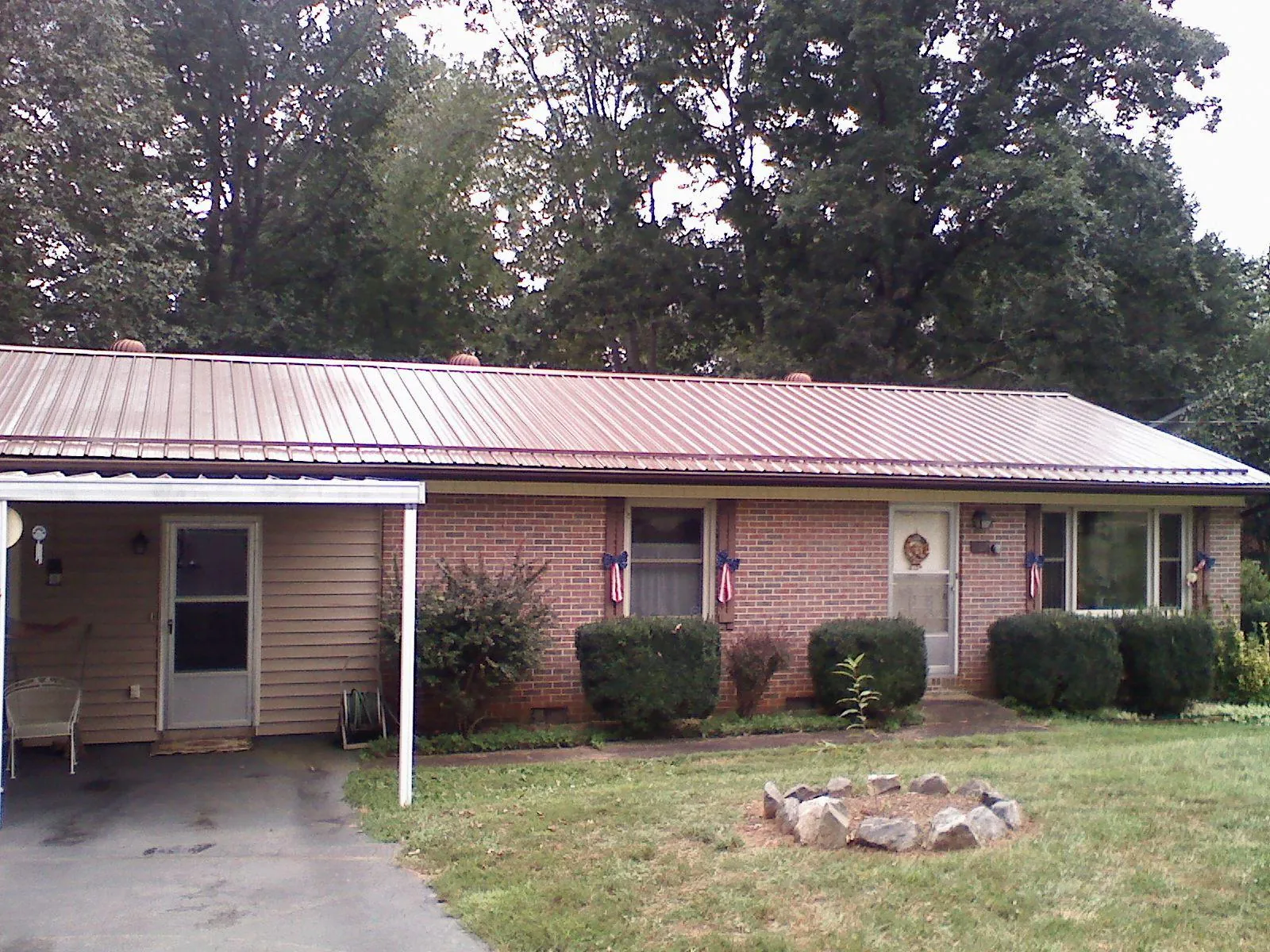 Bronze metal roof and carport on a brick ranch home — Roof Repair work by our crew in Amesville